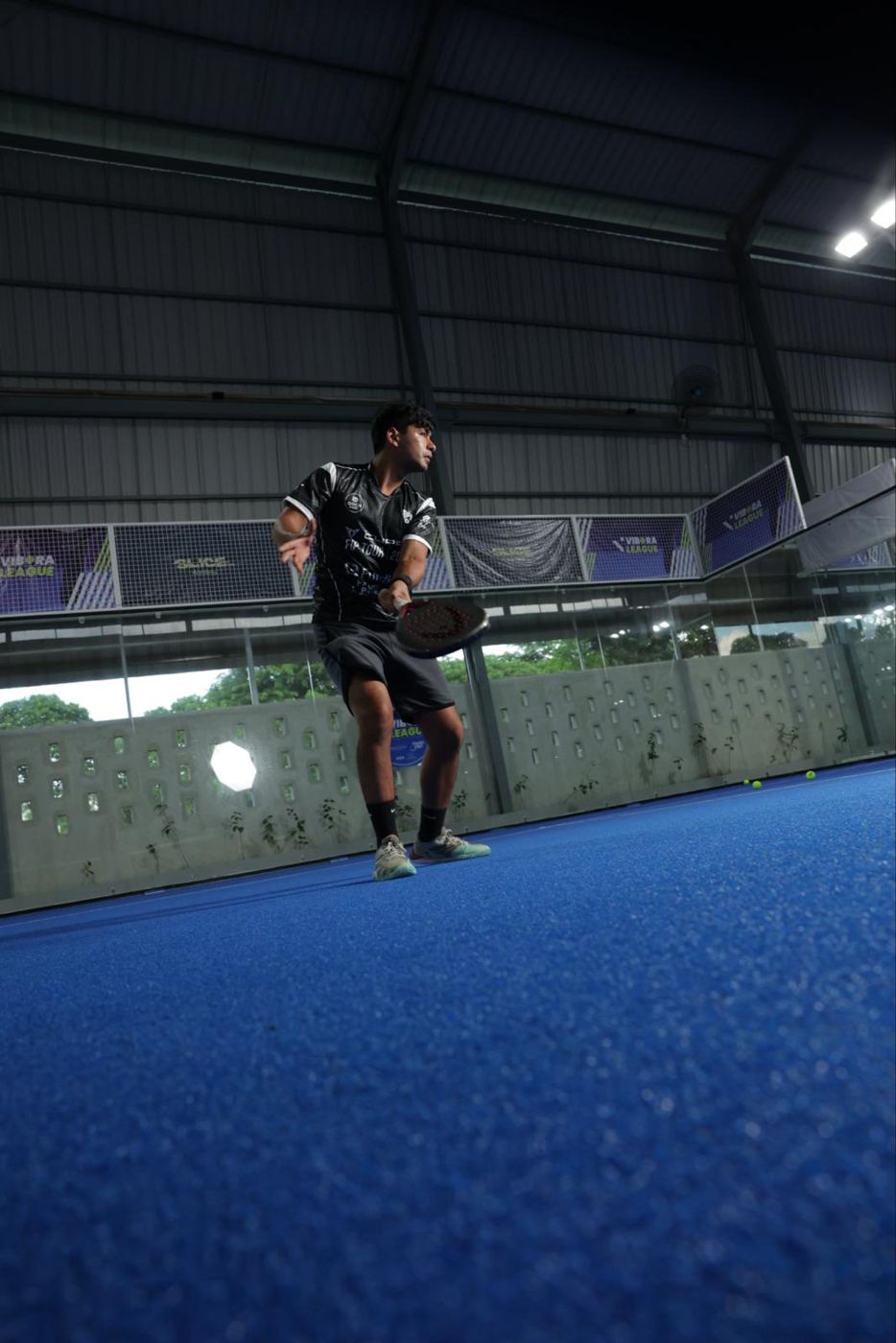 Naser setting up a backhand on a blue court