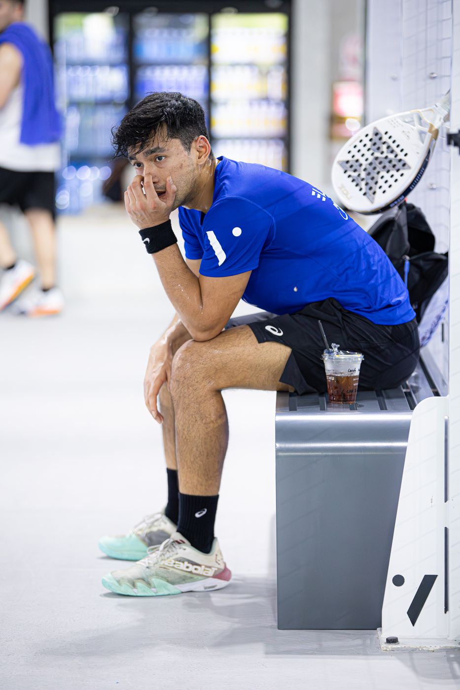 Naser resting on a courtside bench between matches