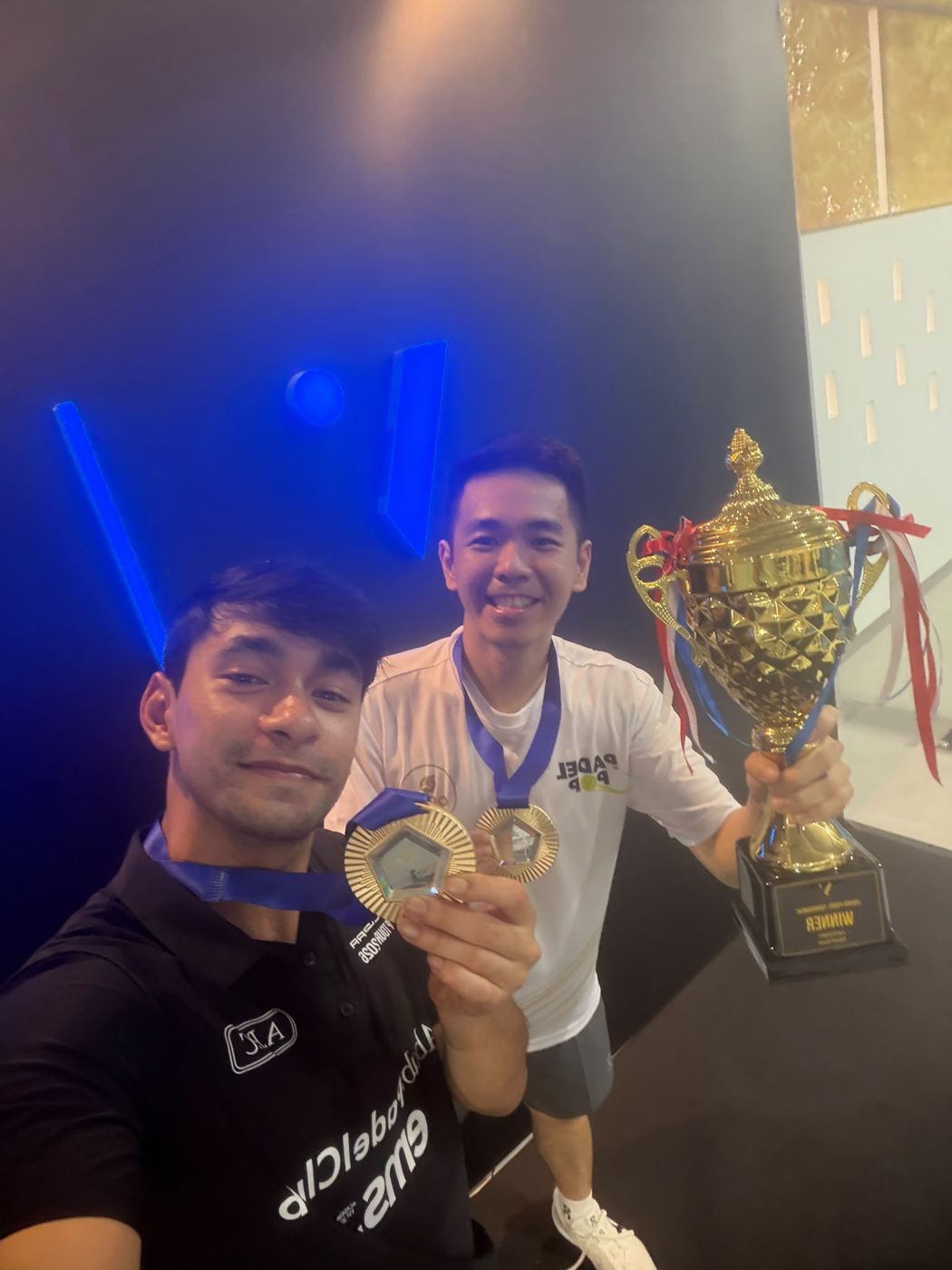 Naser holding two gold medals with the winner's trophy in Batam